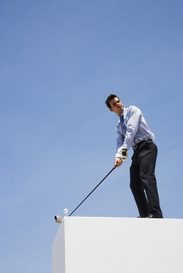 站在高处打高尔夫球的商务男士图片