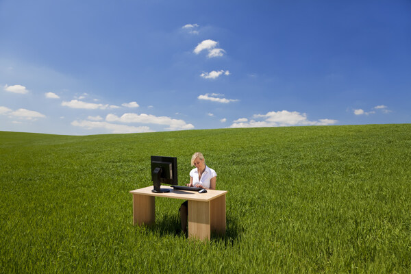 蓝天白云绿草地上玩电脑的外国女性图片