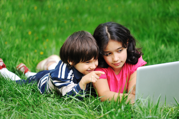 趴草地上玩电脑的儿童图片