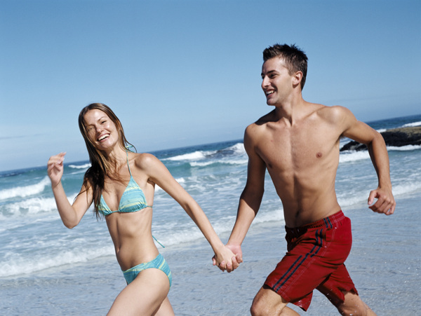 手牵手奔跑在沙滩上的情侣图片