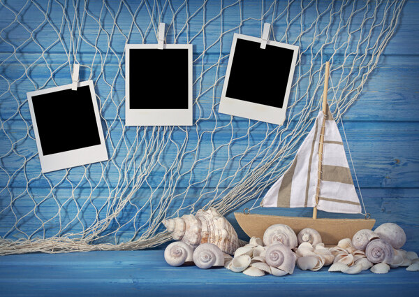木板前的渔网帆船海螺和相框图片